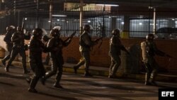 Miembros de la Guardia Nacional Bolivariana (GNB) permanecen alerta hoy, lunes 17 de febrero de 2014, durante protestas registradas en el sector Los Ruices, cerca al canal de televisión estatal "Venezolana de Televisión" (VTV), en Caracas (Venezuela).